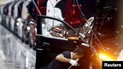 FILE - An employee works on an assembly line producing Mercedes-Benz cars at a factory of Beijing Benz Automotive Co. in Beijing, Aug. 31, 2015. 