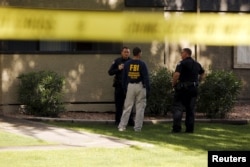 An investigator talks to police officers at the Autumn Ridge apartment complex which had been searched by investigators in Phoenix, Arizona, May 4, 2015.