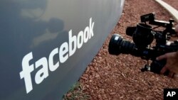 FILE - A television photographer shoots the sign outside of Facebook headquarters in Menlo Park, Calif., May 18, 2012.