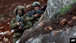 Israeli soldiers stand guard at the site of their excavation work, near the southern border village of Mays al-Jabal, Lebanon, Dec. 13, 2018.