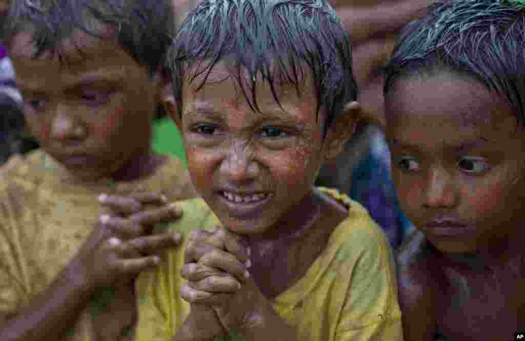 Anak-anak pengungsi menggigil kedinginan di tengah hujan di kamp darurat untuk warga Rohingya di Sittwe, Burma (14/5). Televisi pemerintah melaporkan Senin (13/5) bahwa 5.158 pengungsi telah direlokasi dari kamp tersebut ketempat yang lebih aman. Namun masih banyak orang yang rentan. (AP/Gemunu Amarasinghe)