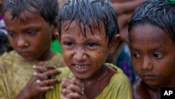 Internally displaced Rohingya boys shiver in rain in a makeshift camp for Rohingya people in Sittwe, Burma, May 14, 2013.