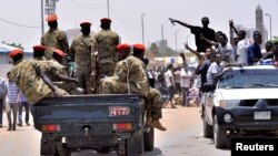 Sudanese demonstrators cheer as they drive towards a military vehicle, celebrating the ouster of President Omar al-Bashir, near the Defense Ministry in Khartoum, Sudan, April 11, 2019.