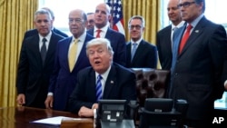 FILE - In this March 24, 2017, photo, President Donald Trump announces the approval of a permit to build the Keystone XL pipeline, clearing the way for the $8 billion project in the Oval Office of the White House in Washington. From left are, TransCanada CEO Russell K. Girling, Commerce Secretary Wilbur Ross and Energy Secretary Rick Perry.