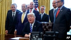 FILE - In this March 24, 2017, photo, President Donald Trump announces the approval of a permit to build the Keystone XL pipeline, clearing the way for the $8 billion project in the Oval Office of the White House in Washington. From left are, TransCanada 