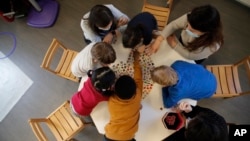 FILE - Children play with a therapist in the pediatric unit of the Robert Debre hospital, in Paris, France.