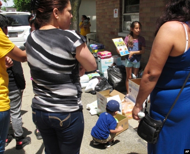 FILE - A boy picks out a soccer ball from donations delivered to an Ohio trailer park in Norwalk, Ohio, June 15, 2018. Community members donated diapers, baby wipes, food and clothing for the families of workers arrested in an immigration raid at a garden and landscaping company in early June.