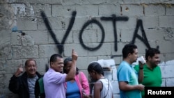 Gradjani čekaju da glasaju za članove Ustavotvorne skupštine pored zida na kojem su ispisane reči "glasajte", Karakas, Venecuela 30. juli, 2017