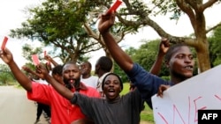 Roman Catholic priest Frank Bwalya (in red) and supporters hold red cards to display their displeasure with the government as they attend a rally in front of the National Assembly, in Lusaka, Zambia, March 22, 2011.