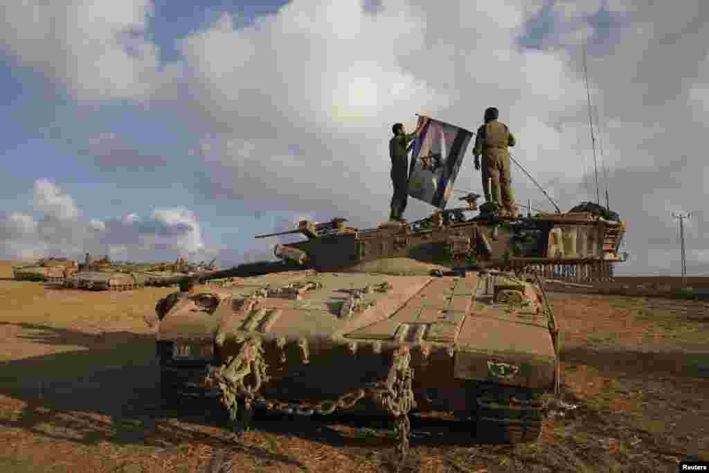 Israeli soldiers place their national flag atop a tank at a staging area near border with the Gaza Strip, Aug. 4, 2014.