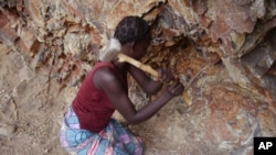 FILE - A woman rock-crusher hits rocks with a hammer in a quarry in Maroua, Cameroon, June 16, 2016.