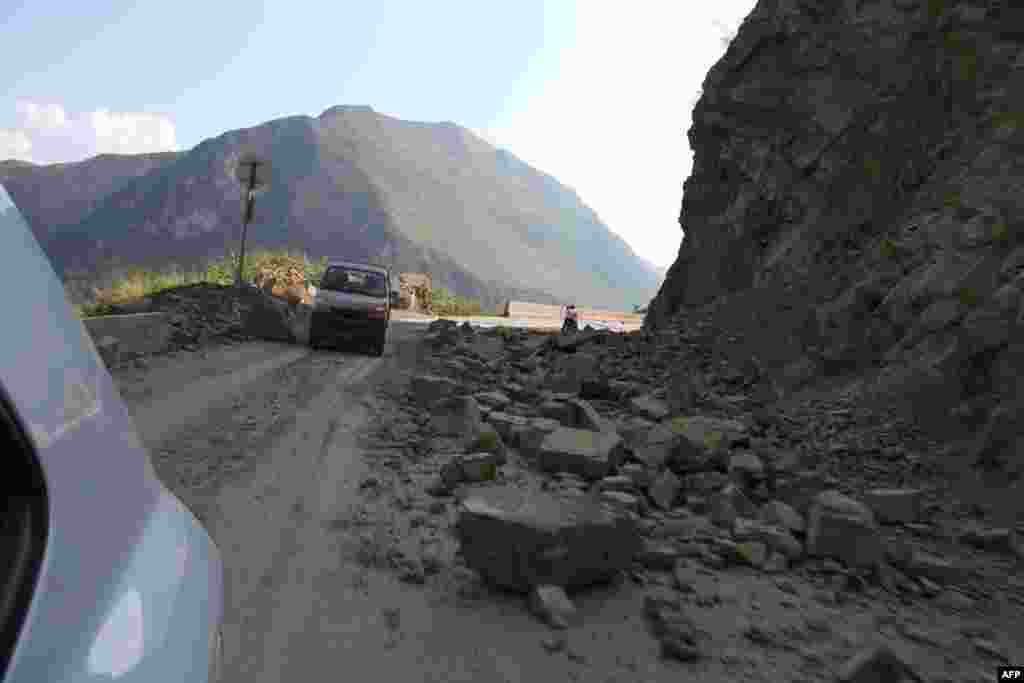 Vehicles make their way slowly along the road after a rock-fall in Yiliang, southwest China's Yunnan province, Sept. 7, 2012.