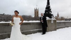 How not to dress for the cold: a newly married couple poses for a photograph opposite the Houses of Parliament in London on Saturday. Snow brought much of Britain to a standstill.