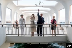 U.S. President Donald Trump and first lady Melania Trump, accompanied by Command Commander Adm. Harry Harris, left, and his wife, Bruni Bradley, scatter pikake petals while visiting the Pearl Harbor Memorial in Honolulu, Hawaii, Nov. 3, 2017. The president quietly said “thank you” a couple of times.