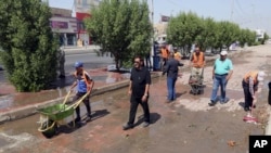 Iraqi municipality workers clean the scene of a suicide attack in Baghdad's western Eskan neighborhood, Iraq, Sunday, Sept. 25, 2016. A suicide bomber killed several people who were setting up tents on Sunday ahead of a major Shi'ite religious observance next month, officials said. 