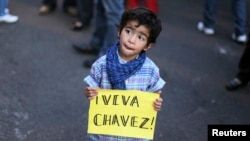 A boy holds a sign that reads "Long live Chavez" during a tribute for the late Venezuelan President Hugo Chavez in Tegucigalpa, March 6, 2013.