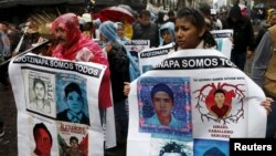 Relatives and friends hold banners with images of some of the 43 missing students as they march in Mexico City to mark the first anniversary of the students' disappearance, Sept. 26, 2015.
