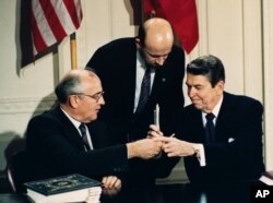 1987年苏联领导人戈尔巴乔夫和美国总统里根(右)在签署美苏中程核导弹条约后换笔（1987年12月8日）