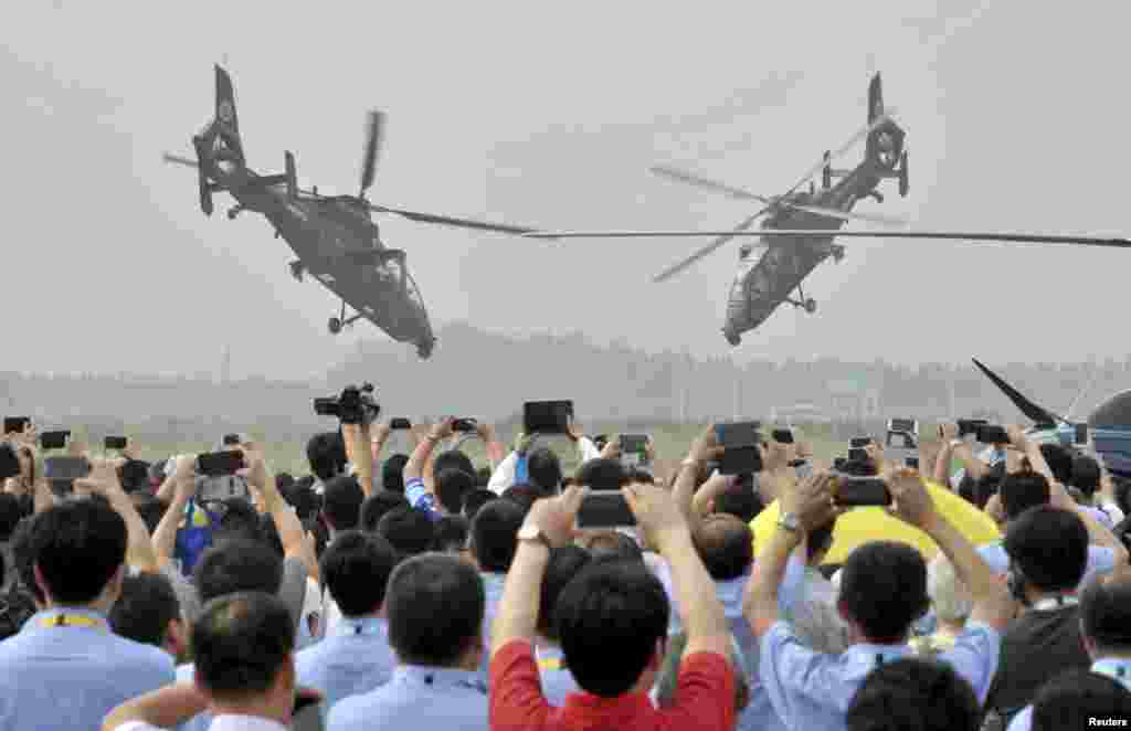 Spectators use their mobile phones to take pictures and videos as Z-19 helicopters of the People's Liberation Army (PLA) perform during an aerobatic display at the China Helicopter Exposition in Tianjin.