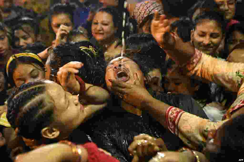 Devotees drink wine from a statue of Shwet Bhairav (god of protection) during the Indra Jatra festival in Kathmandu, Nepal.