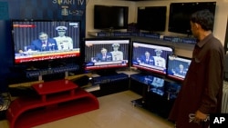 A Pakistani man listens to President Asif Ali Zardari's speech to joint session of parliament, on televisions at an electronics shop in Islamabad, March 17, 2012. 