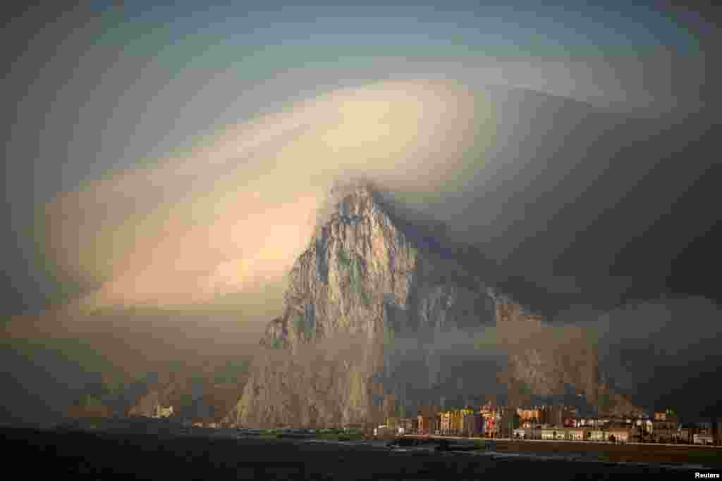 A cloud partially covers the Rock of the British territory of Gibraltar at sunrise from La Atunara port before Spanish fishermen sail with their relatives to take part in a protest at an area of the sea where an artificial reef was built by Gibraltar using concrete blocks, Algeciras bay, La Linea de la Concepcion, southern Spain, Aug. 18, 2013.