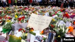 Members of the public stand behind a note that can be seen amongst floral tributes that have been placed near the cafe where hostages were held for over 16-hours, in central Sydney December 16, 2014. Heavily armed Australian police stormed a Sydney cafe e