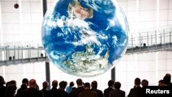 Germany's Chancellor Angela Merkel (wearing blue jacket) and delegates look at a computerized model of the earth "Geo-Cosmos" while visiting Miraikan (National Museum of Emerging Science and Innovation) in Tokyo March 9, 2015. REUTERS/Issei Kato