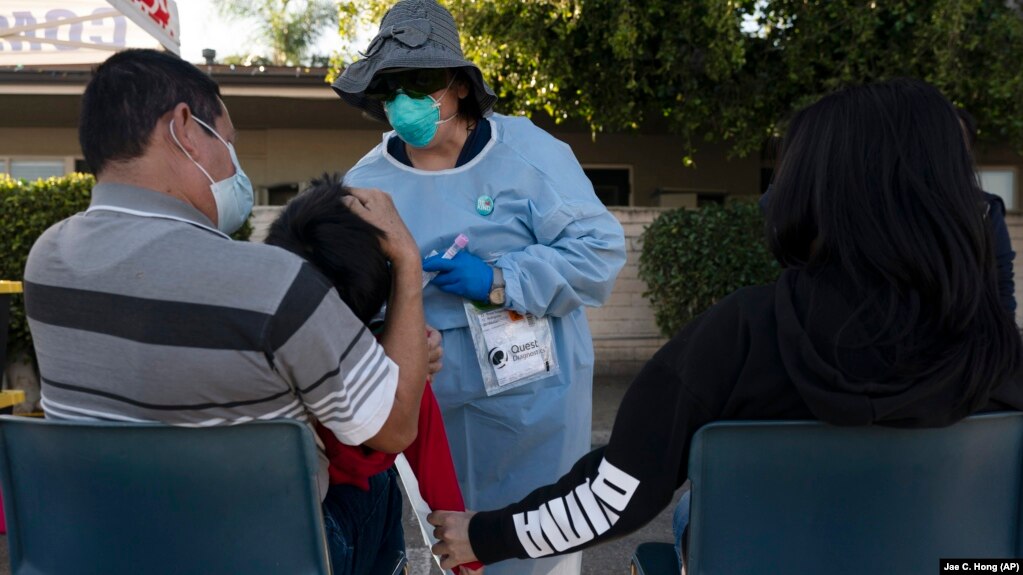 Medical official Rita Ray collects tissue from Sebastian Henandez, 5, for a COVID-19 test at Families Together of Orange County community health center in Tustin California on January 6, 2022. (AP Photo/Jae C. Hong, File)