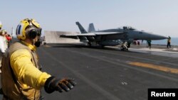 A flight deck crew member is seen giving an 'all clear' before a F/A-18C Hornet takes off from the aircraft carrier USS George H.W. Bush in the Persian Gulf August 12, 2014.