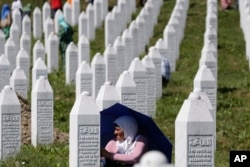 FILE - A Bosnian Muslim woman protects herself from the sun during a funeral ceremony for dozens of newly identified victims of the 1995 Srebrenica massacre, at the Srebrenica memorial center of Potocari, 150 km northeast of Sarajevo, Bosnia, July 11, 2017.