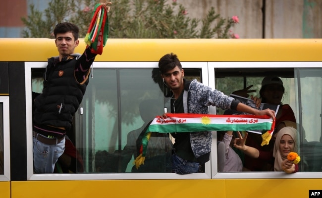 FILE - Iraqi Kurds wave fabric strips in the colors of the Kurdish flag during a rally in support of Iraqi Kurdish leader Masoud Barzani, in Irbil, Iraqi Kurdistan, Oct. 30, 2017.