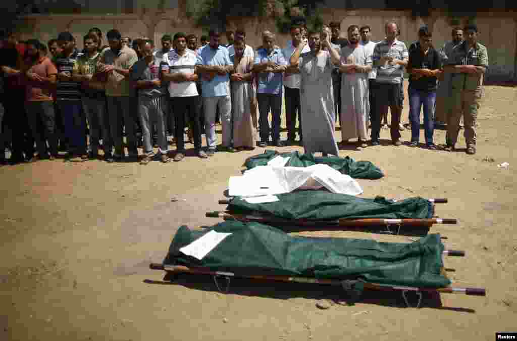 People pray next to the bodies of Palestinians from the al-Silk family during their funeral in Gaza City July 31, 2014.