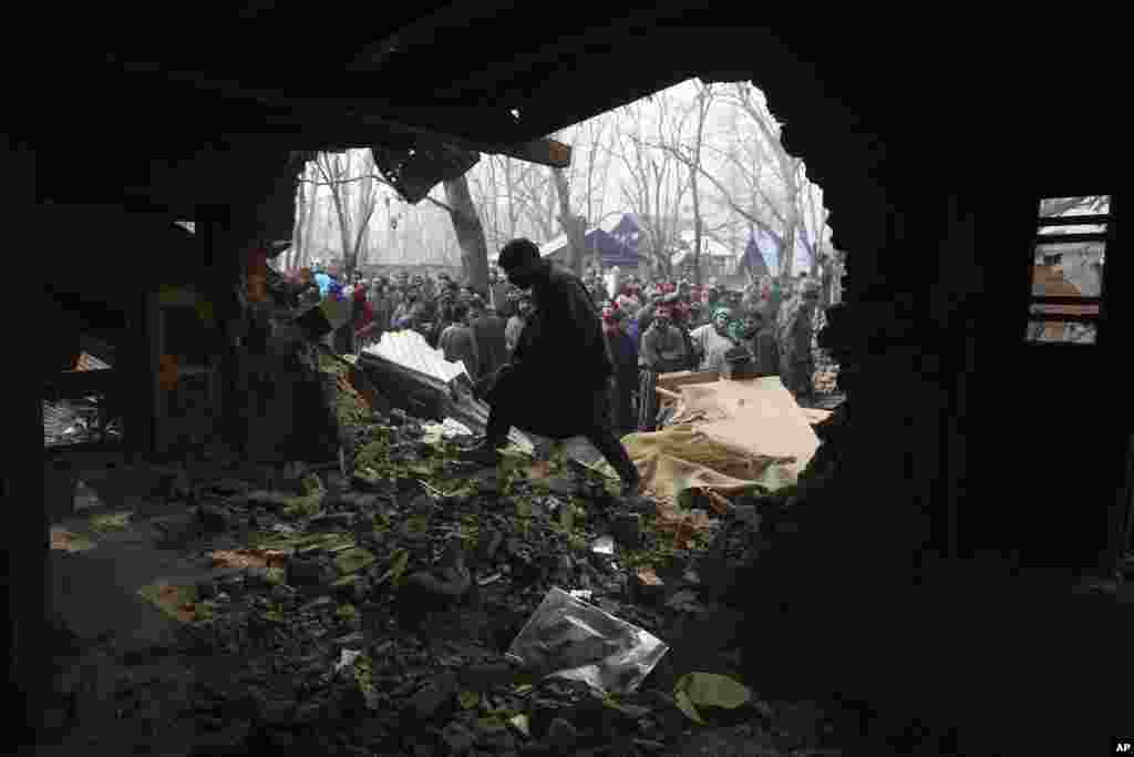 A Kashmiri villager walks across the house which was damaged during a gun-battle at Shopian 55 kilometers south of Srinagar, Indian controlled Kashmir.