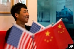 一位16岁的中国学生在北京一家教育机构里的美中两国国旗旁（2014年6月26日）