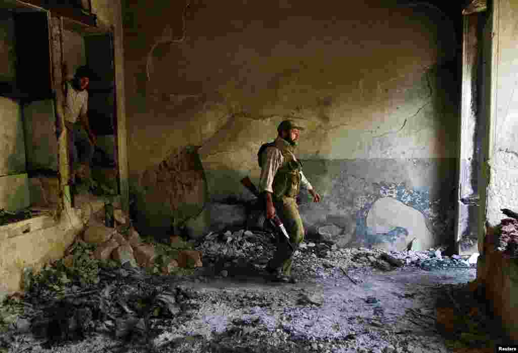 Free Syrian Army fighters walk inside a damaged house near the Hanano Barracks in Aleppo, Sept. 3, 2013. 