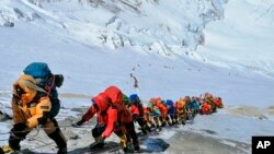 In this May 22, 2019 photo, a long queue of mountain climbers line a path on Mount Everest just below camp four, in Nepal. (AP Photo/Rizza Alee)