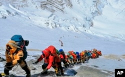 In this May 22, 2019 photo, a long line of mountain climbers line a path on Mount Everest just below camp four, in Nepal.