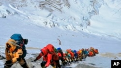 FILE - Mountain climbers line a path on Mount Everest just below camp four, in Nepal, May 22, 2019.