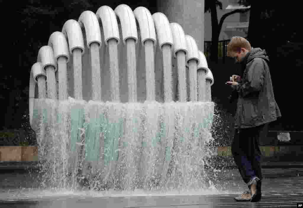 A man uses his mobile phone in front of an artwork at a park in Tokyo, Japan.