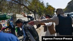 FILE - Taliban members (R) attack journalists covering a women's rights protest in Kabul on October 21, 2021.