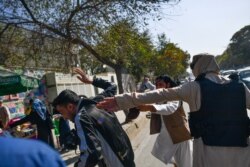 FILE - Taliban members (R) attack journalists covering a women's rights protest in Kabul on October 21, 2021.