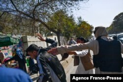 FILE - Taliban members (R) attack journalists covering a women's rights protest in Kabul on October 21, 2021.