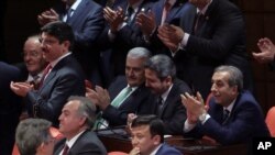 Binali Yildirim, center left, Turkey's current transportation minister, tapped by the ruling party as a candidate for prime minister, applauds with legislators after the vote on a constitutional amendment on parliamentary immunity in Ankara, May 20, 2016. 
