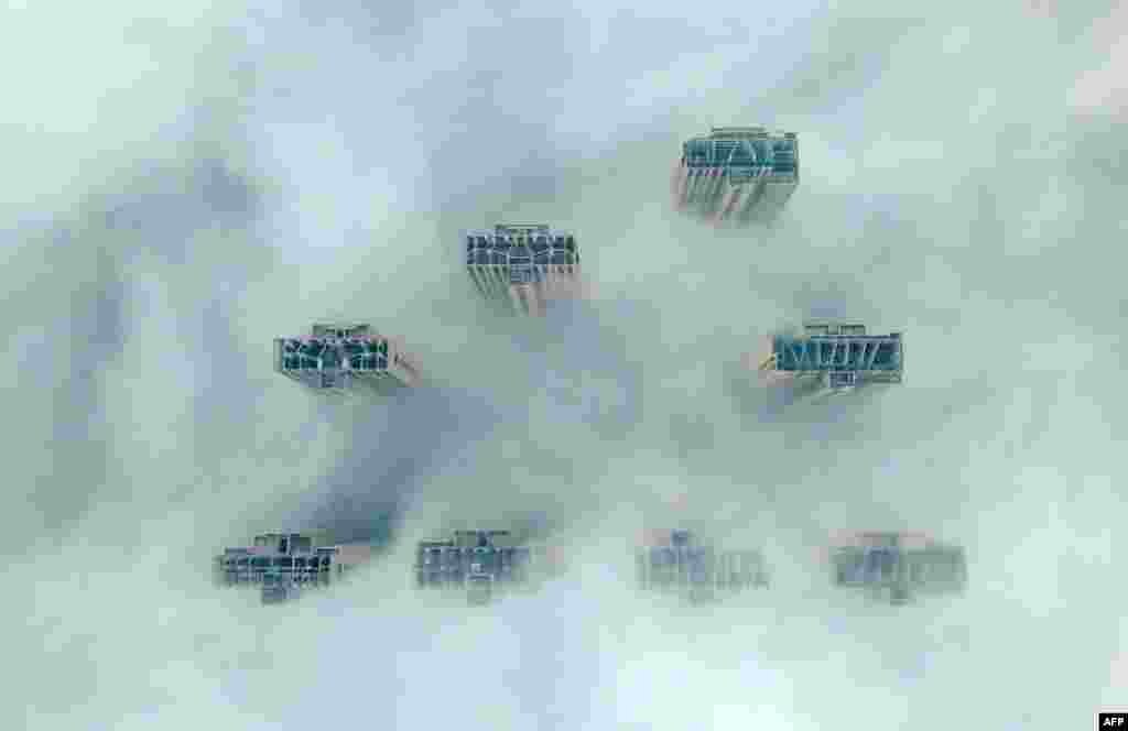 This aerial view shows the tops of high-rise buildings poking out from heavy fog in Yangzhou, in China&#39;s eastern Jiangsu province.