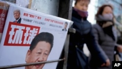 2 medam kap mache bò kote yon ansèy ki genyen foto Prezidan Lachin lan, Xi Jinping, ak foto Prezidan Ameriken, Donald Trump, nan Peken 9 fevriye, 2017.
(Foto: AP/Andy Wong)