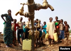 FILE - Congolese refugees, displaced by fighting between the Congo army and rebel group Allied Democratic Forces (ADF), gather around dry water taps at a transit camp southwest of Kampala, July 17, 2013.