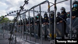 FILE - Thai police stand behind a barbed wire fence in efforts to stop street protests, Bangkok, Thailand, June. 24, 2021. (Tommy Walker/VOA)