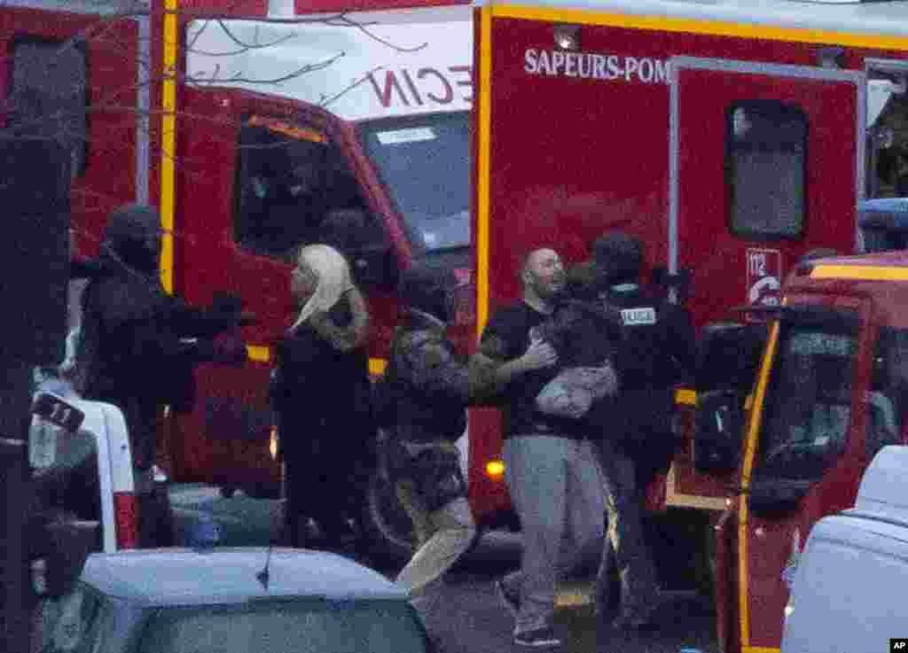 A security officer directs released hostages after they stormed a kosher market to end a hostage situation, Paris, Jan. 9, 2015.