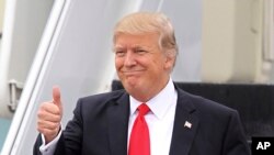 Prezidan Donald Trump kap fè jès salitasyon pandan lap mache desann eskalye avyon Air Force One nan sou pis Ayewopò Entènasyonal West Palm Beach la nan Florid, Etazini, 3 mas, 2017. 